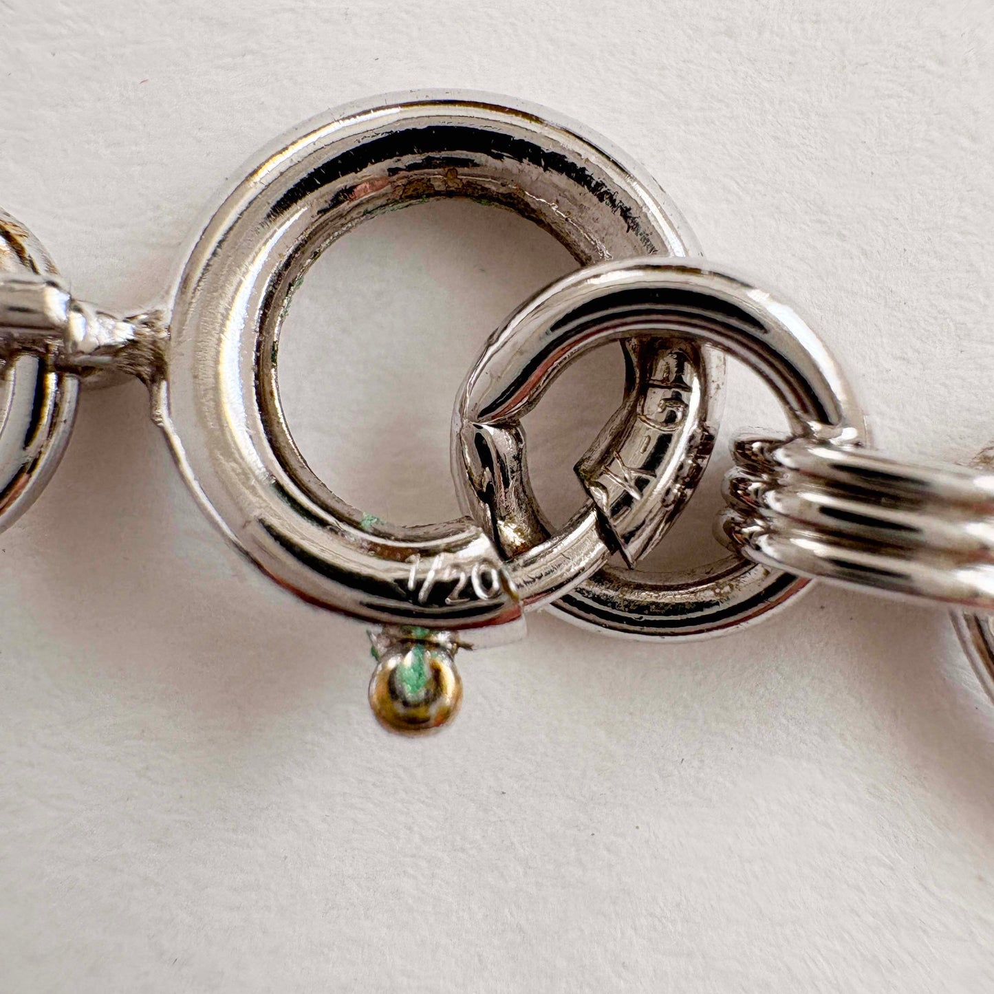 Close-up of a white gold scarab bracelet clasp on a light background