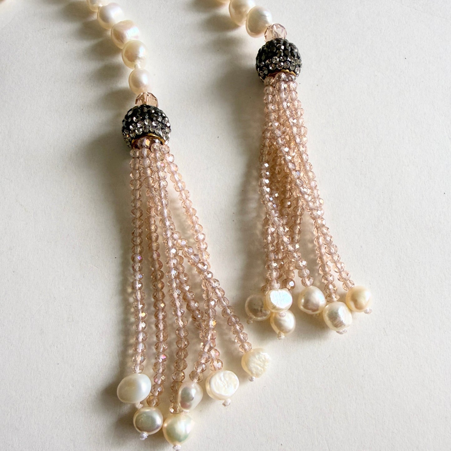 Close-up of shimmering crystalline micro-bead tassels suspended from tiered, champagne-toned pavé crystal spheres.