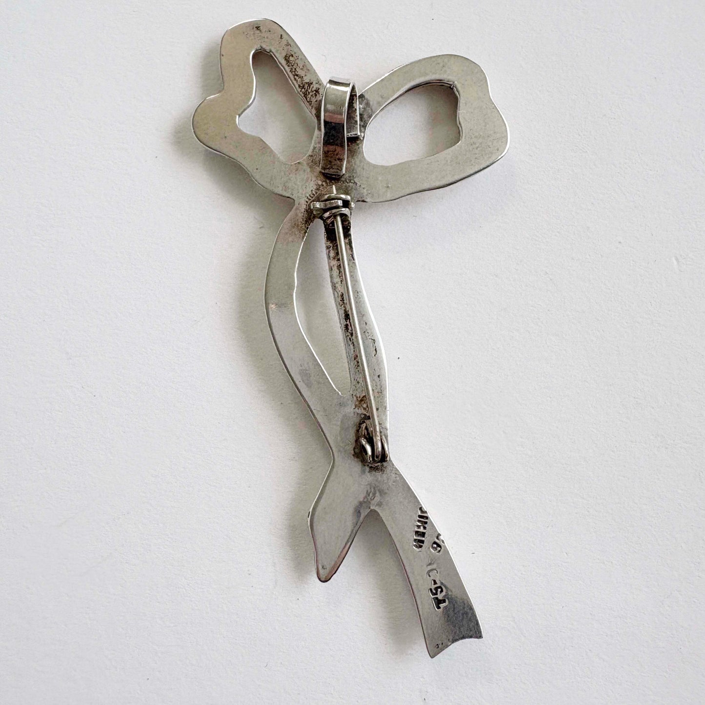 silver bow-shaped brooch on a white background