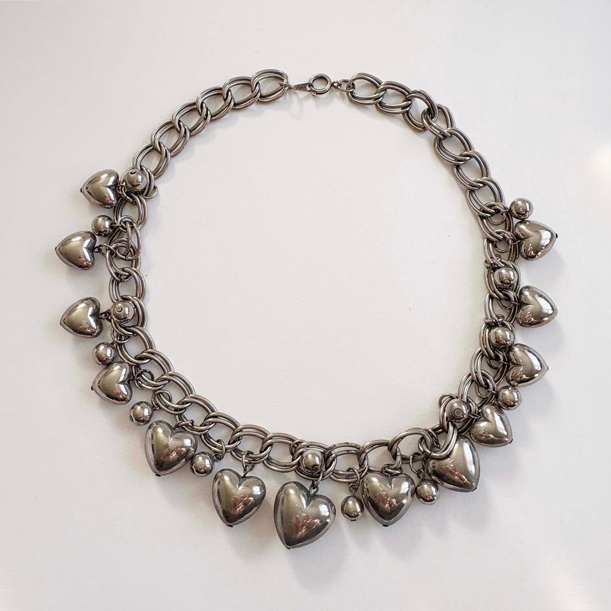silver chain necklace with heart-shaped charms on a white background