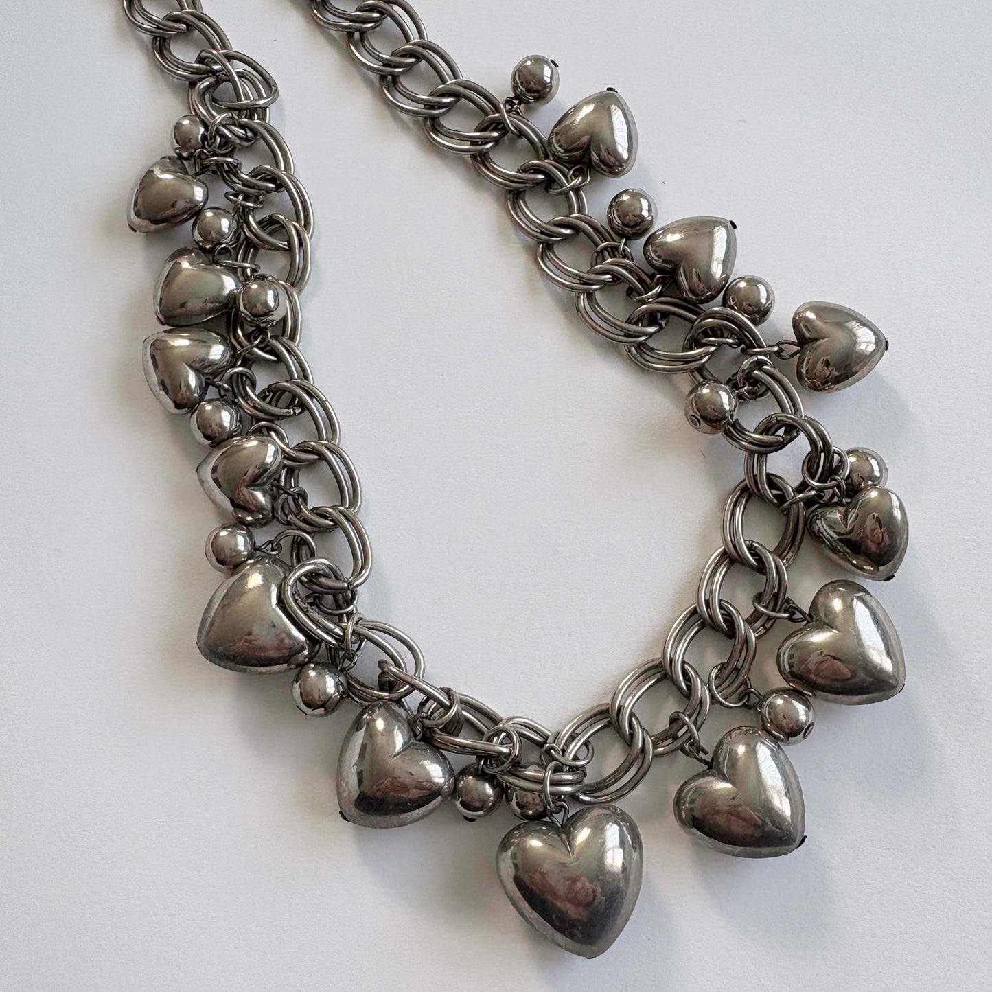 silver chain necklace with heart-shaped charms on a white background