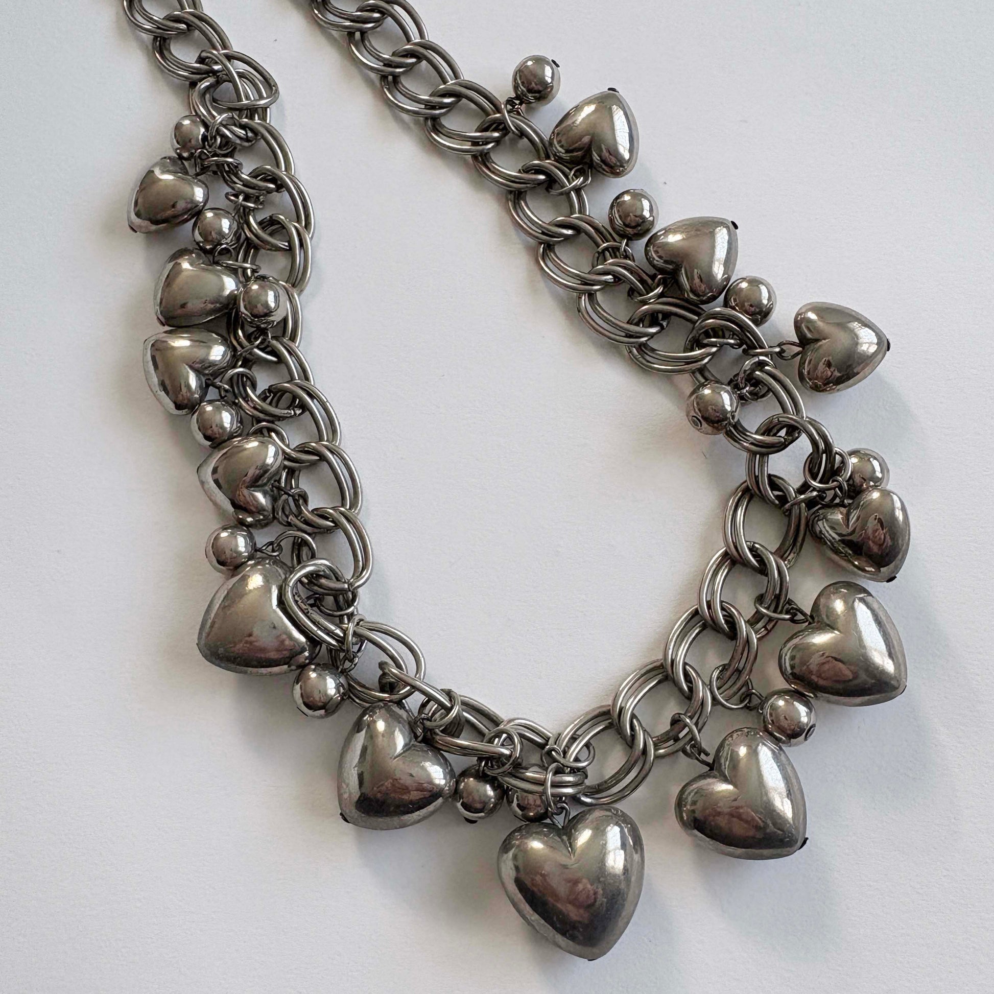silver chain necklace with heart-shaped charms on a white background