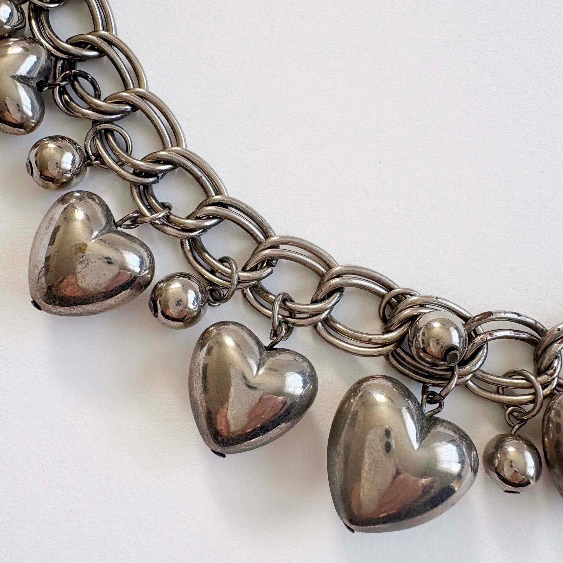 silver chain necklace with heart-shaped charms on a white background