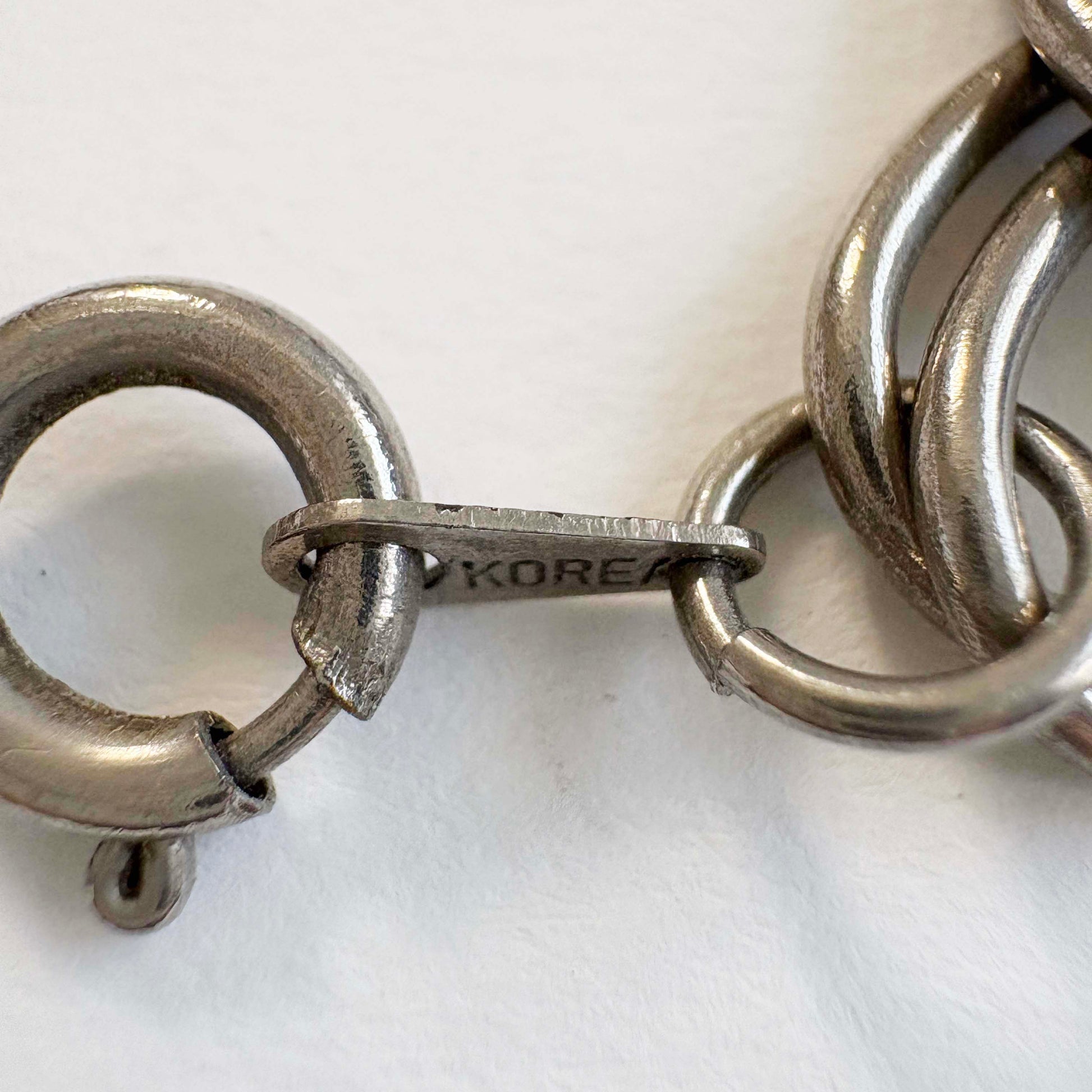 Close-up of a silver chain necklace clasp on a white background
