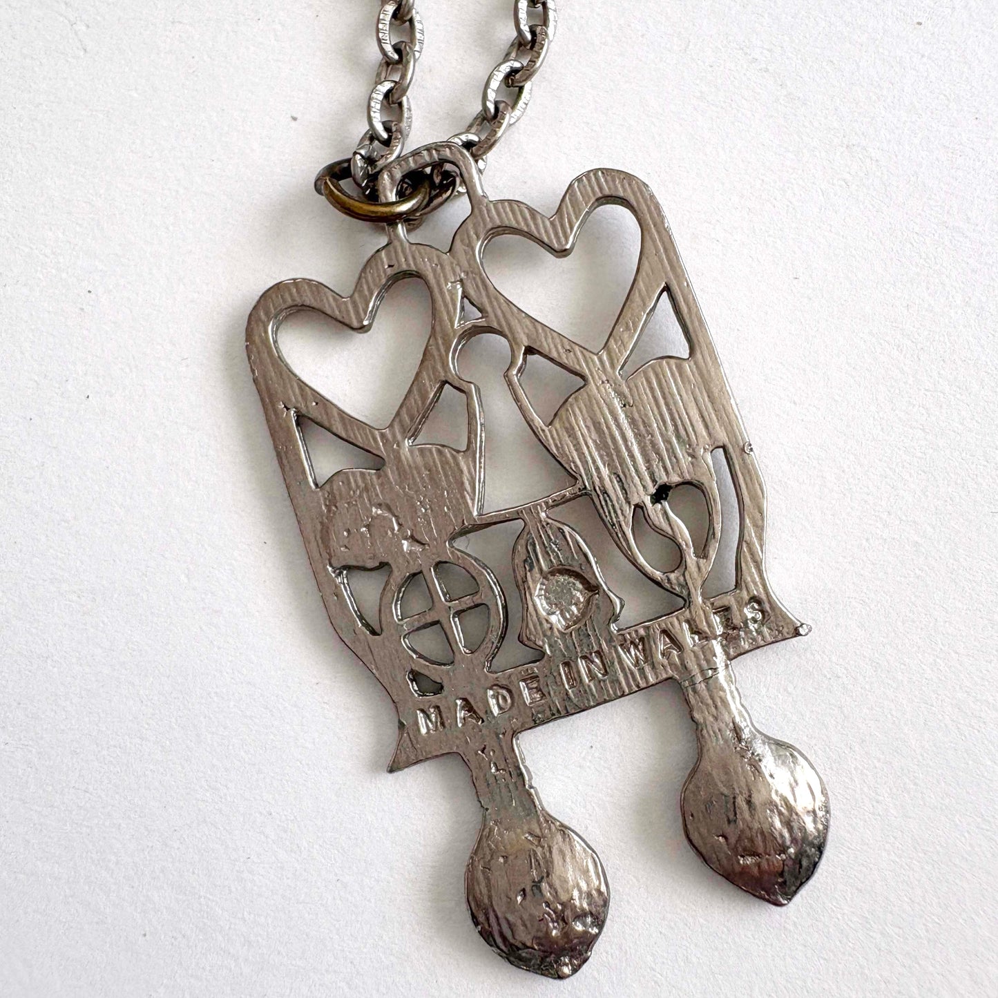 Silver pendant (back side) with Welsh Spoon heart design on a white background