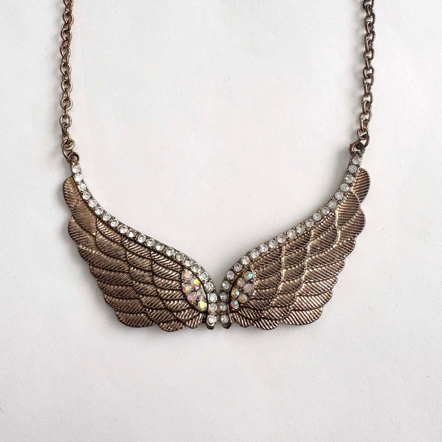 Winged necklace with rhinestones on a light gray background