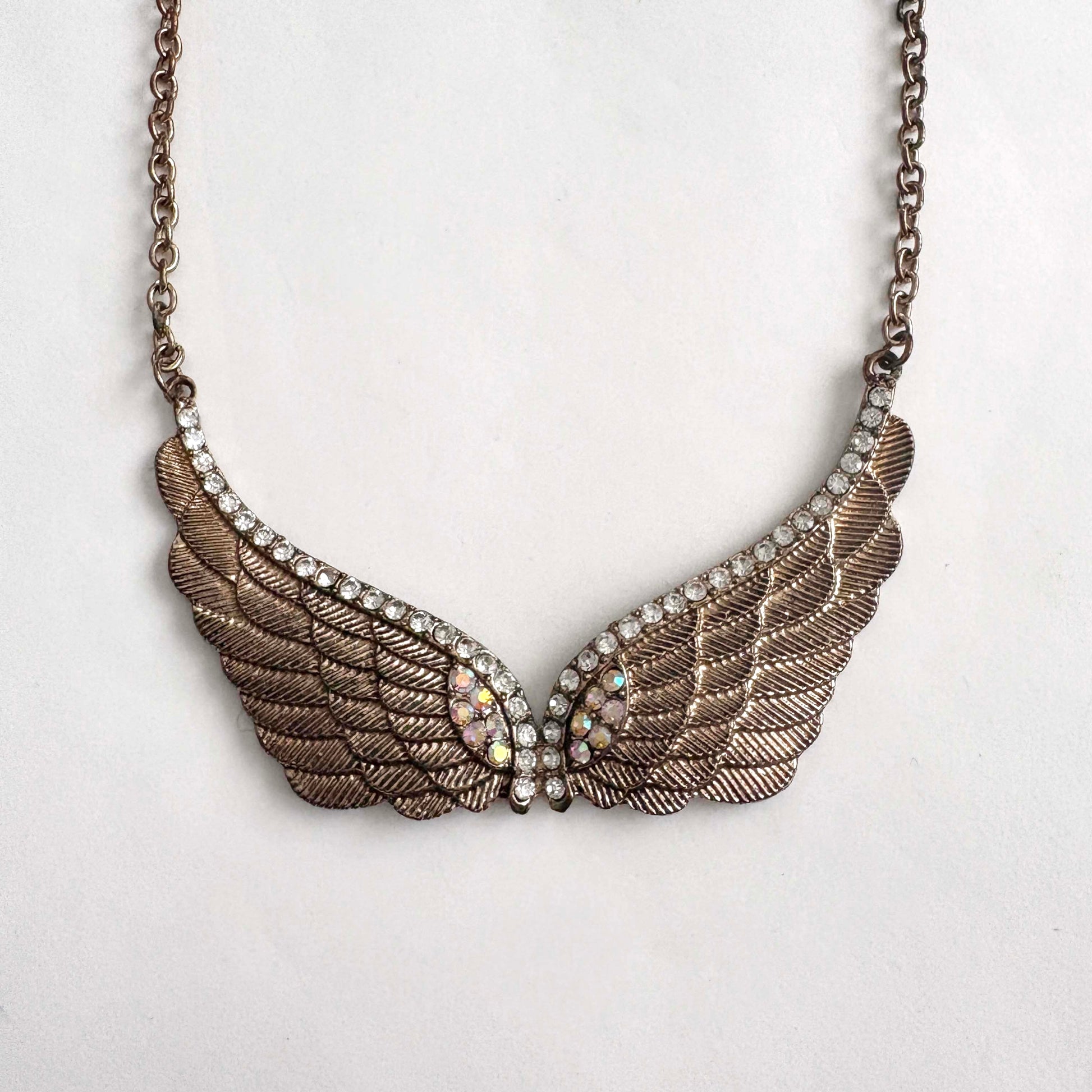 Winged necklace with rhinestones on a light gray background