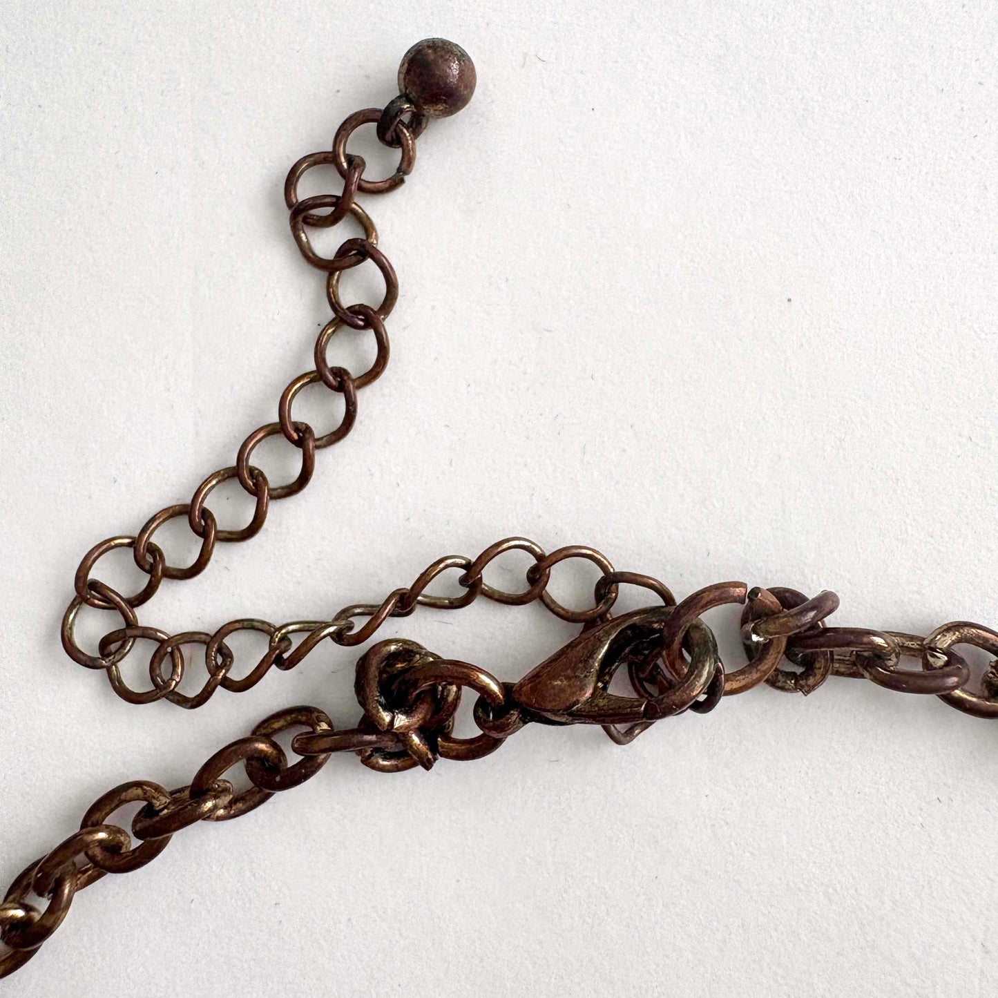 Close-up of a bronze chain necklace and lobster claw on a white background